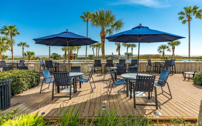 Outdoor dining deck with palm trees and beach view