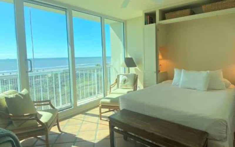 Condo bedroom with floor-to-ceiling Gulf views
